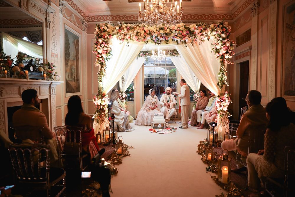 Beautifully decorated wedding ceremony setup with floral arch and candlelit aisle in an elegant ballroom. Asian Wedding Photography & Videog