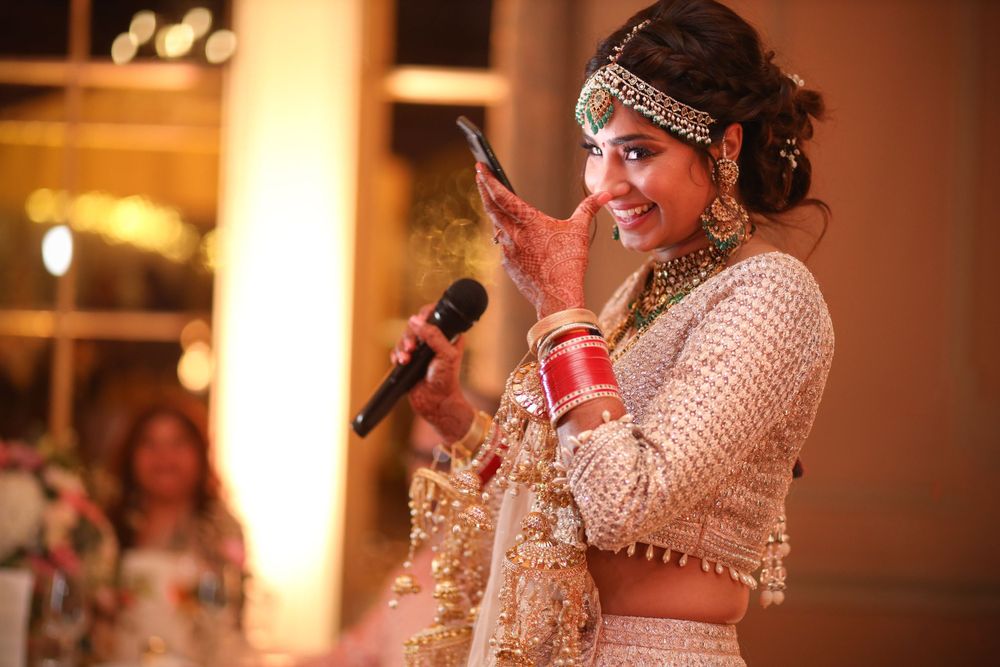 Wedding guest in traditional Indian attire speaks into microphone during reception celebration. Asian Wedding Photography & Videography
