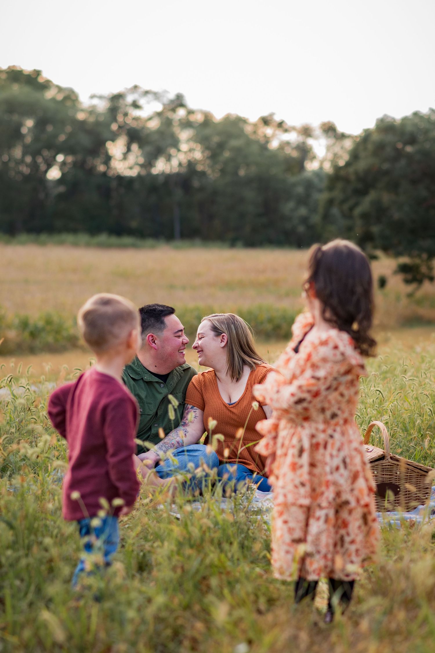 Family enjoys picnic together in wildflower meadow during golden hour.