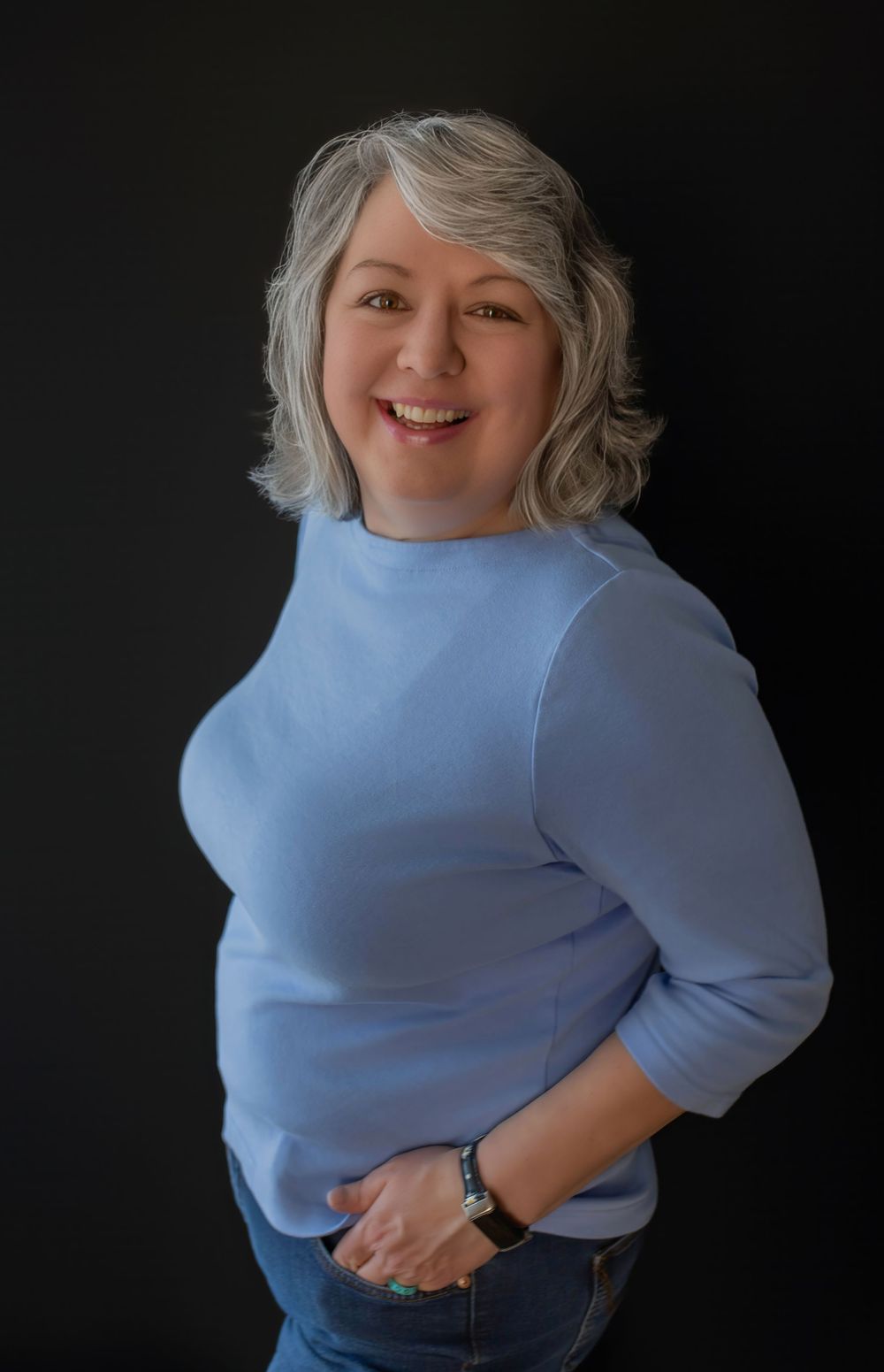 A series of portrait photos against a dark background shows someone wearing a light blue sweater with a warm smile and casual pose.