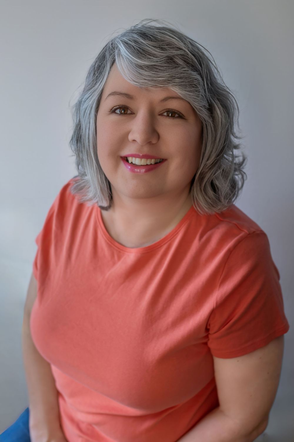 Person wearing a coral-colored t-shirt poses playfully against a light gray background in a series of photos.