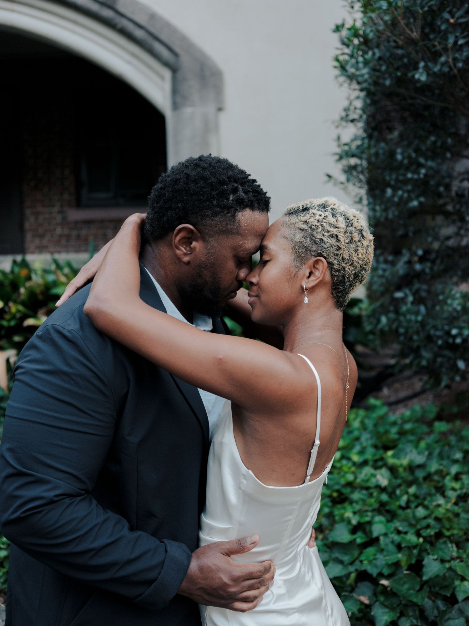 A romantic wedding moment captured in a garden setting with a couple sharing an intimate embrace.
