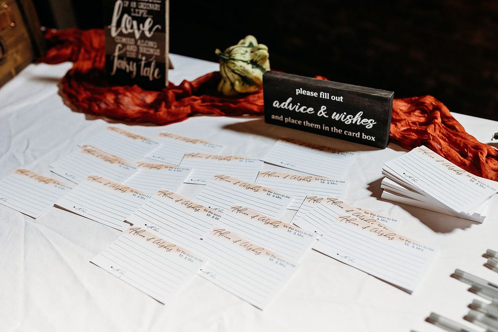 A wedding guest list with red decorations and a black place card displayed on a white tablecloth.
