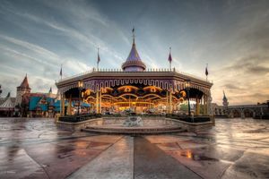 Dramatic panoramic view of Brighton Palace Pier at sunset with moody clouds and reflective wet sand on the beach.