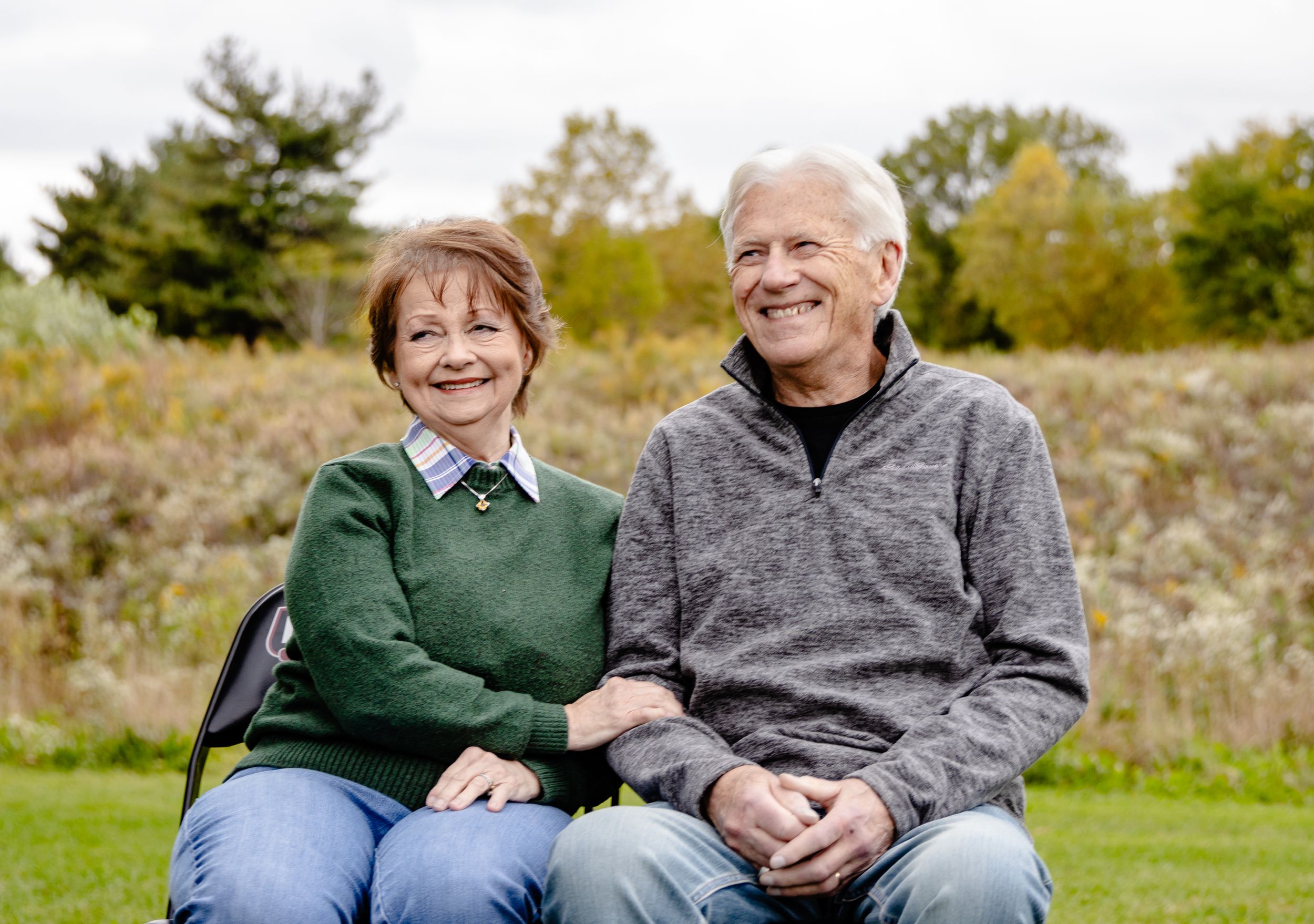 Couple relaxing together on grassy hillside during autumn afternoon.