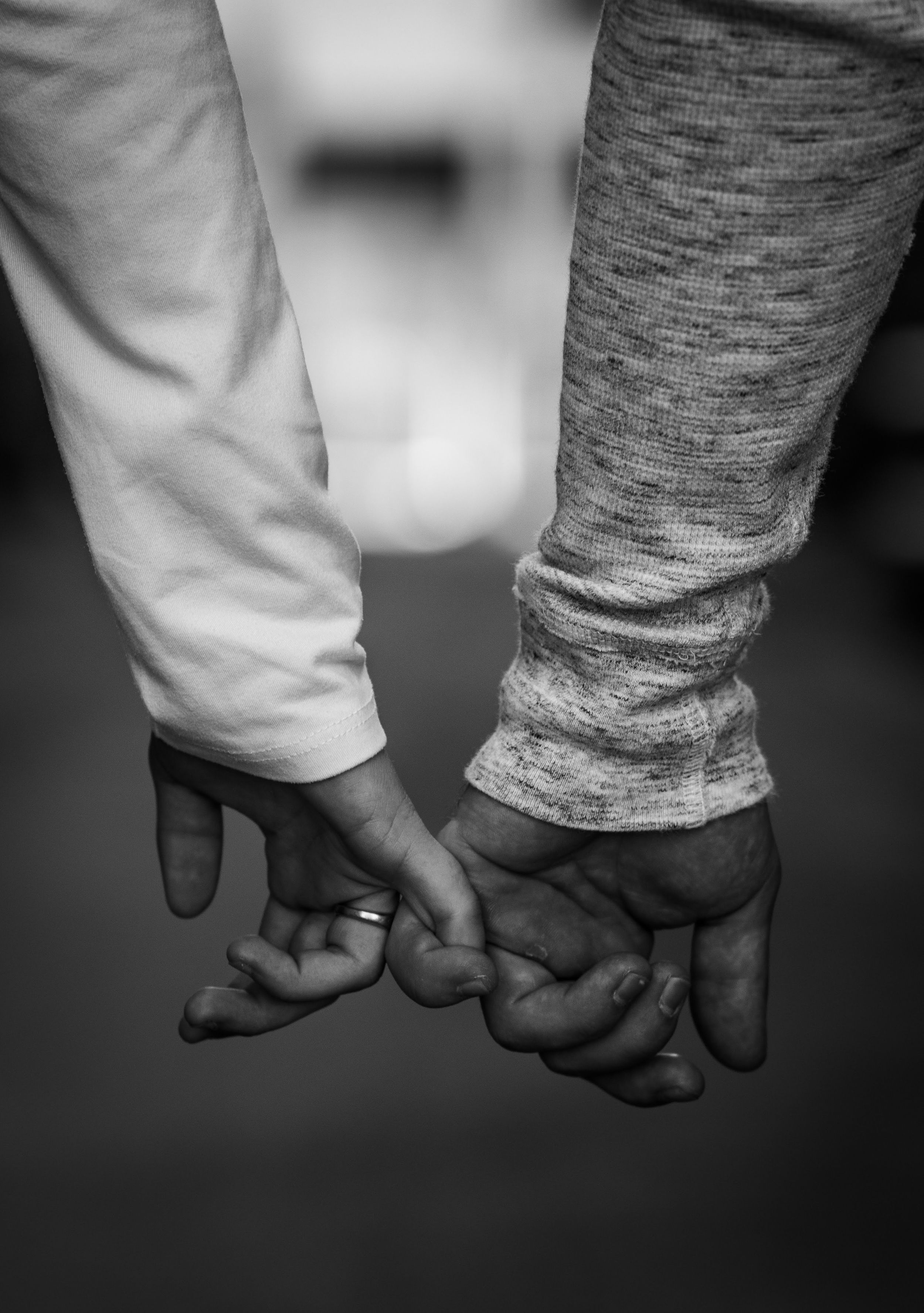 Close-up black and white photo of two hands intimately clasped together.