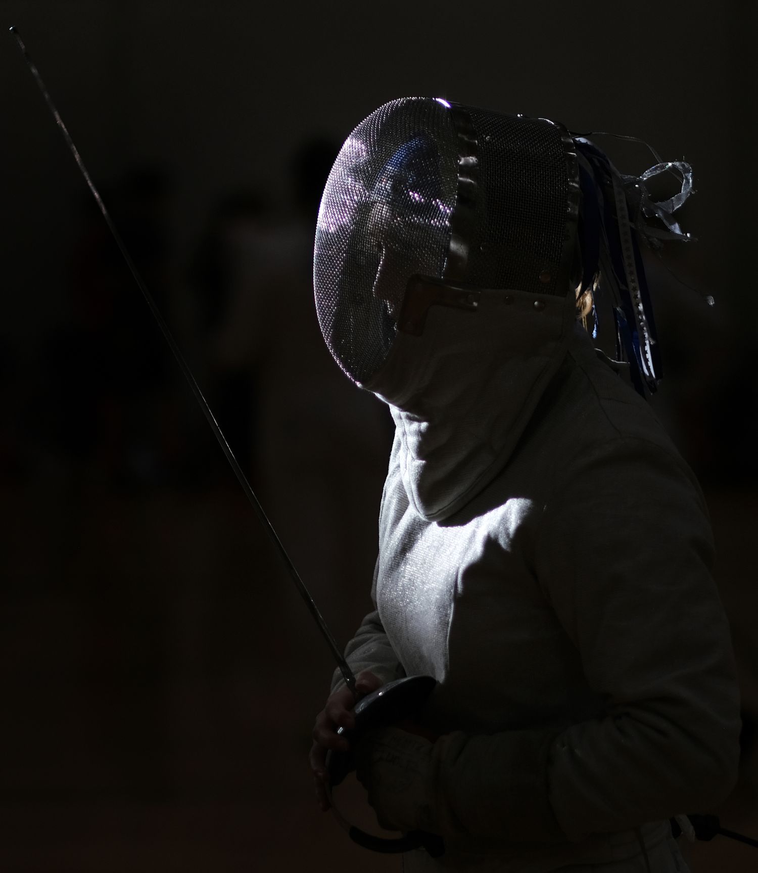 A beam of light is cast on a fencer about to compete in a bout.