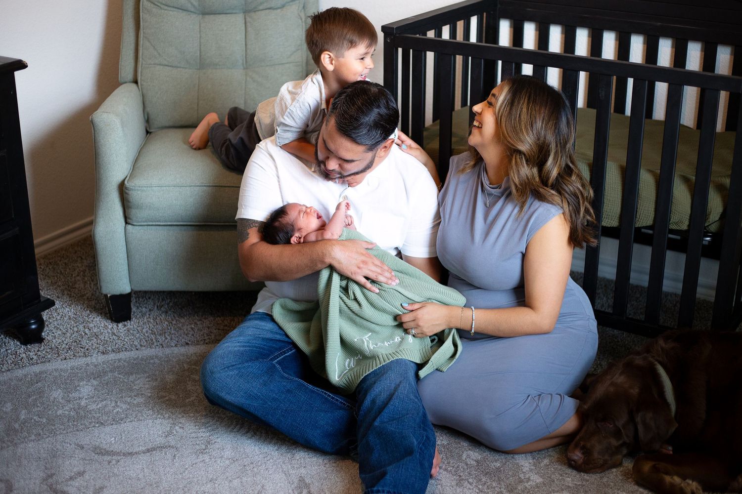 A family shares an intimate moment with their children in a cozy nursery corner.