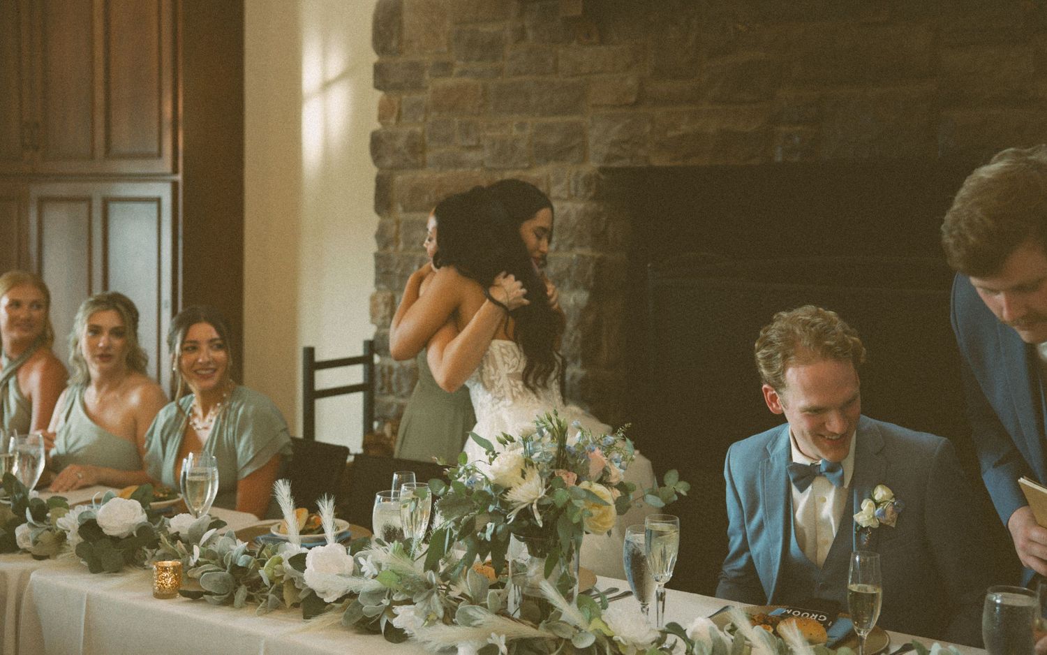 Wedding reception scene at a rustic stone venue with guests seated at an elegantly decorated table.