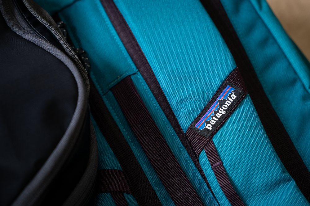 Close-up of a teal Patagonia backpack strap with brand logo.
