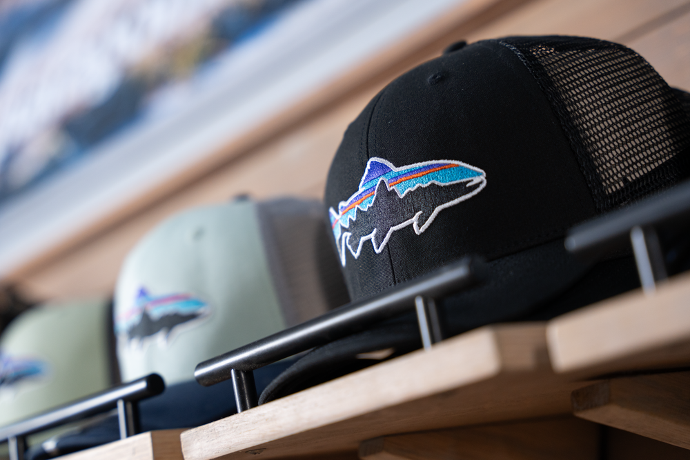 Trucker hat with fish logo displayed on retail shelf.