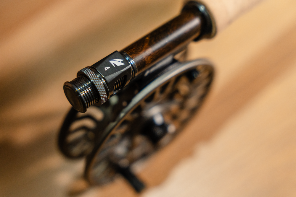 Macro detail of a black fly fishing reel seat and cork handle.