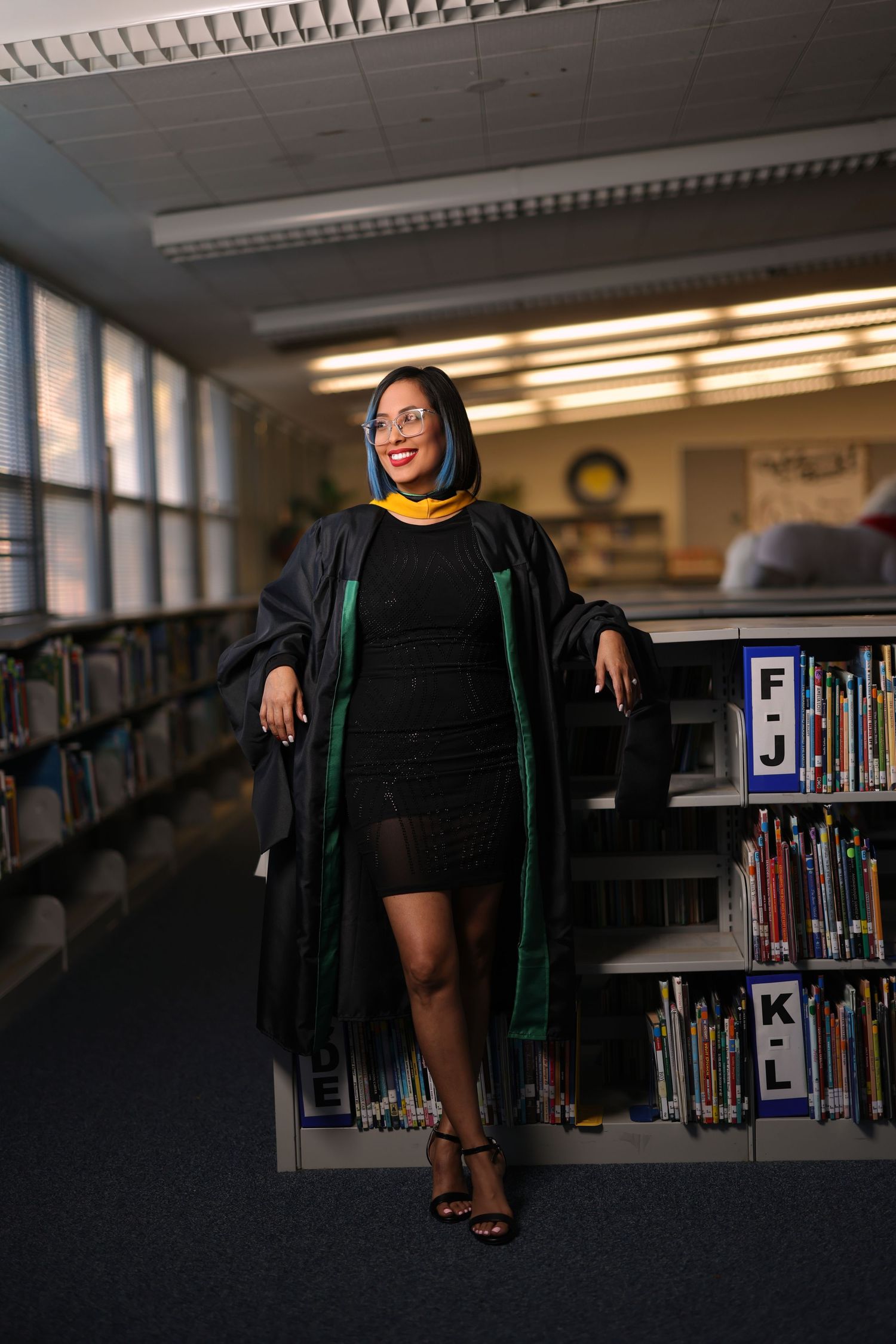 A creative graduation photo series taken in a library showing silhouettes against book shelves.