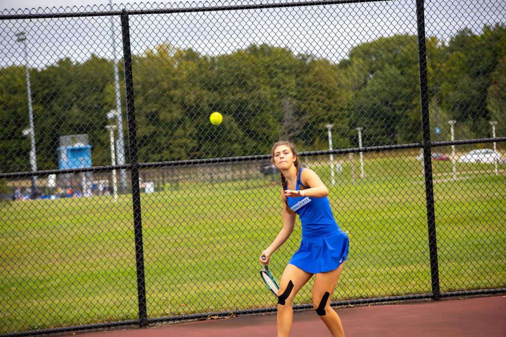 Tennis player in bright blue uniform prepares to hit a forehand shot during a match.