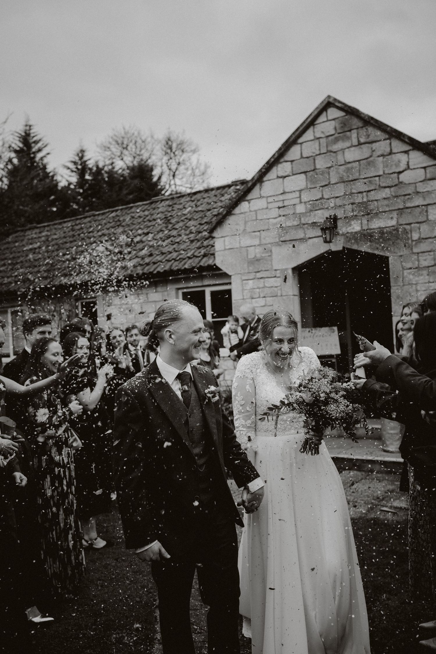 Vintage style black and white photo of wedding couple being showered with confetti.