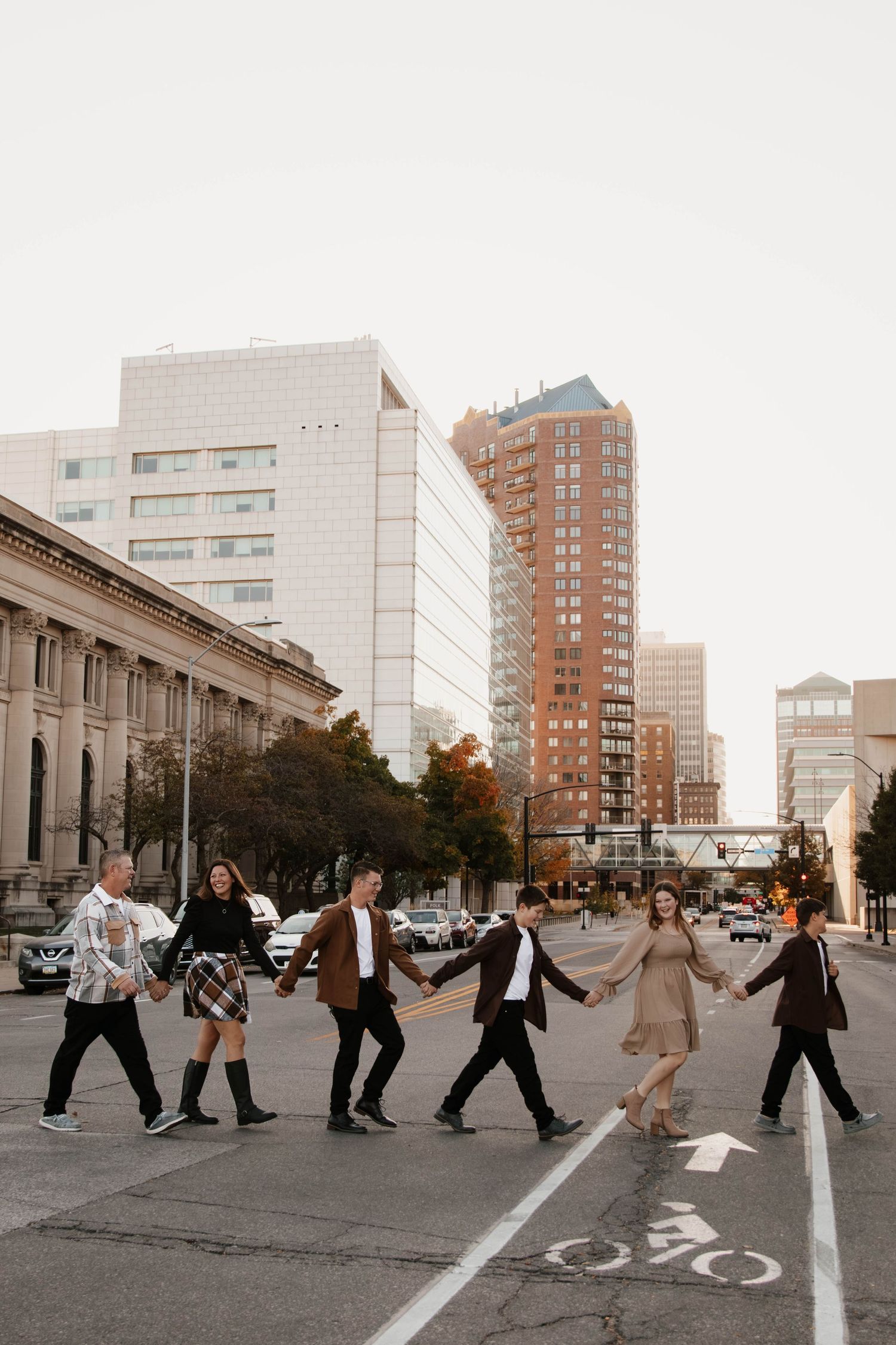 Group walking across city street during sunset with urban buildings in background.