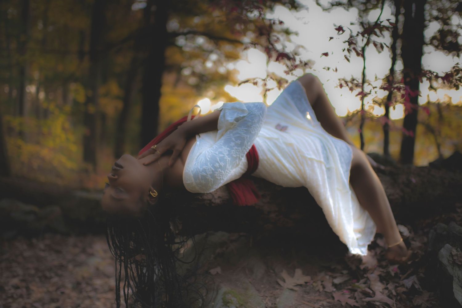 Ethereal scene of figure in white dress floating in autumn forest setting.