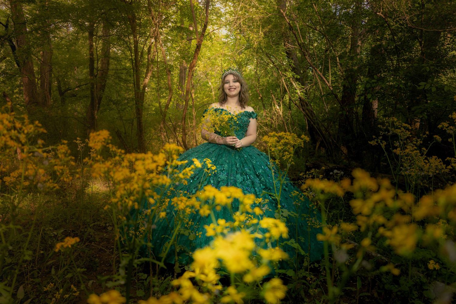 Emerald gown contrasting beautifully with yellow wildflowers in forest setting.