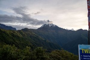 Dramatic mountain peaks rise against cloudy skies in a rugged landscape.