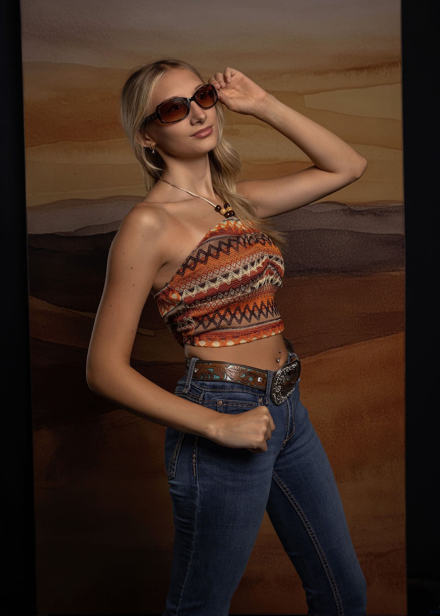 Stylish outfit featuring a one-shoulder patterned crop top paired with high-waisted jeans in a dynamic photo series.