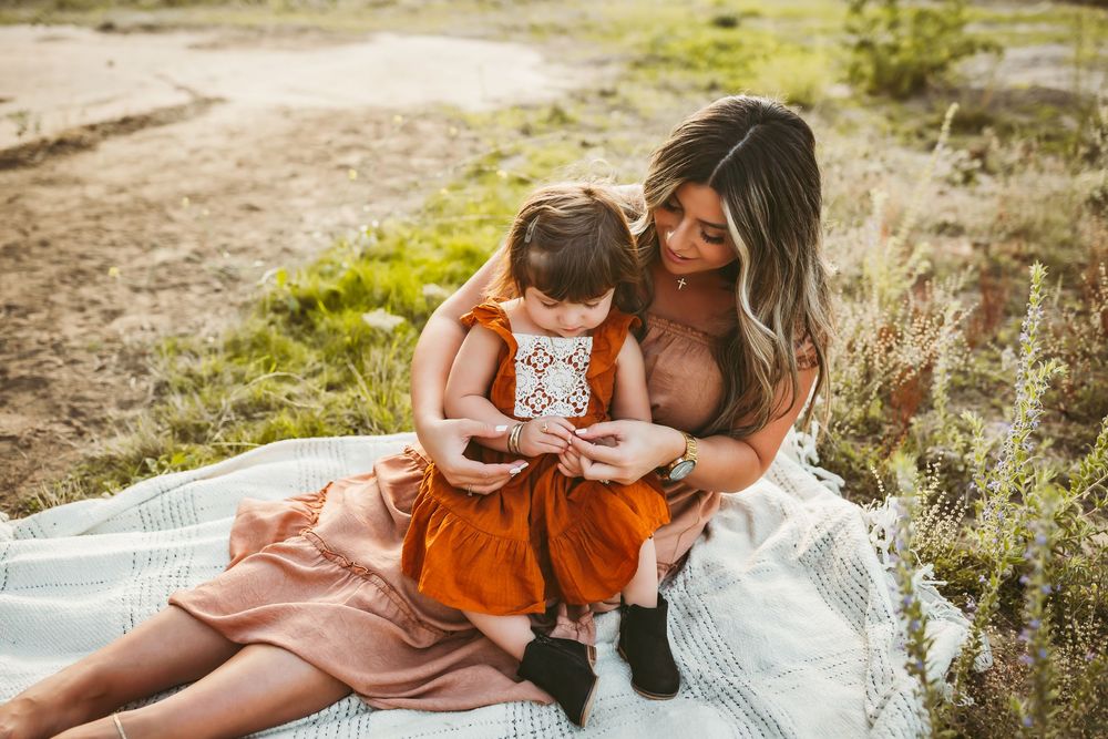 Family enjoying a cozy picnic together on a blanket in a rustic outdoor setting during golden hour.