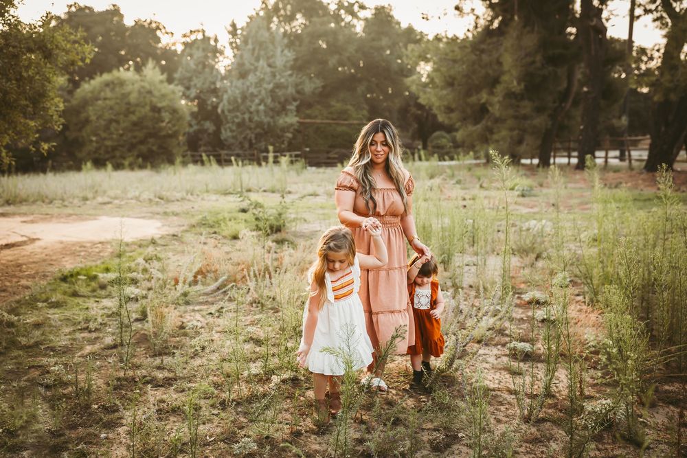 Scenic outdoor photoshoot featuring coordinated outfits in warm sunset lighting among natural grassland.