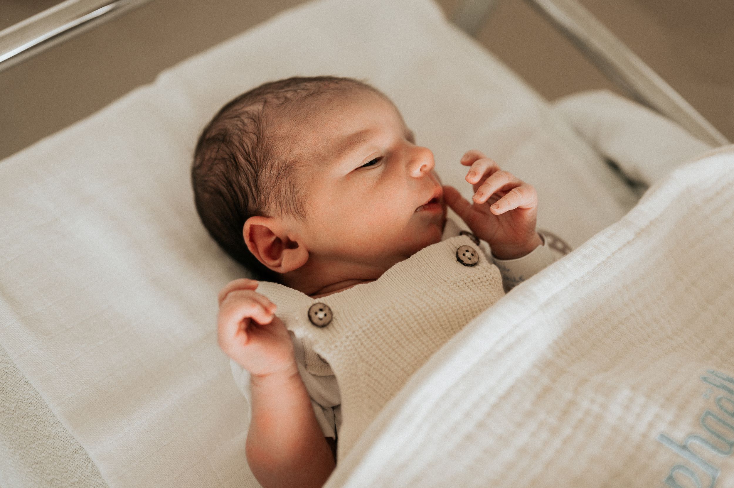 een Newborn baby aan het slapen in een neutraal dekentje tijdens een fresh 48 shoot in het ziekenhuis AZ Delta Roeselare.