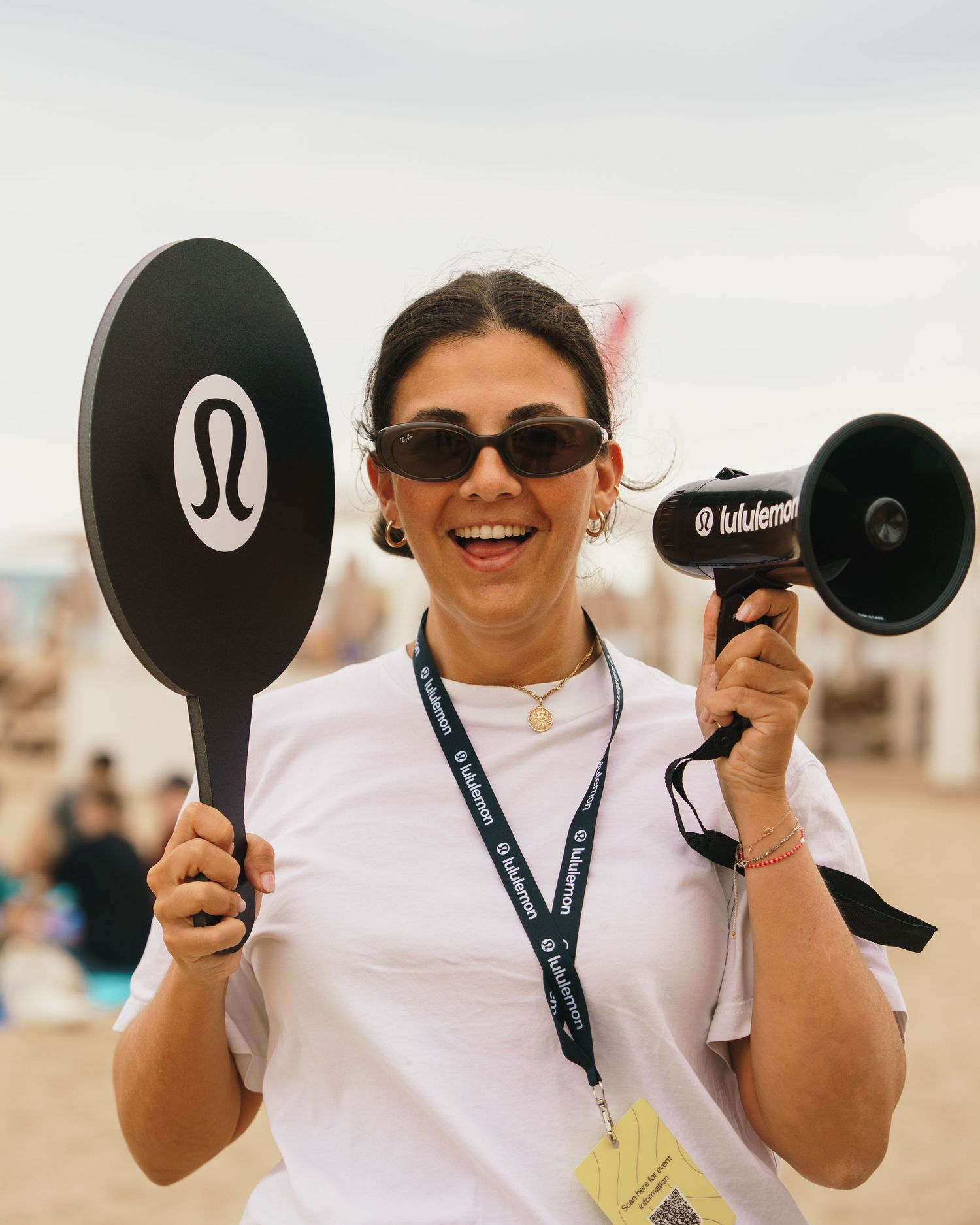 Pickleball players holding up black paddles and smiling while wearing sunglasses on an outdoor court.