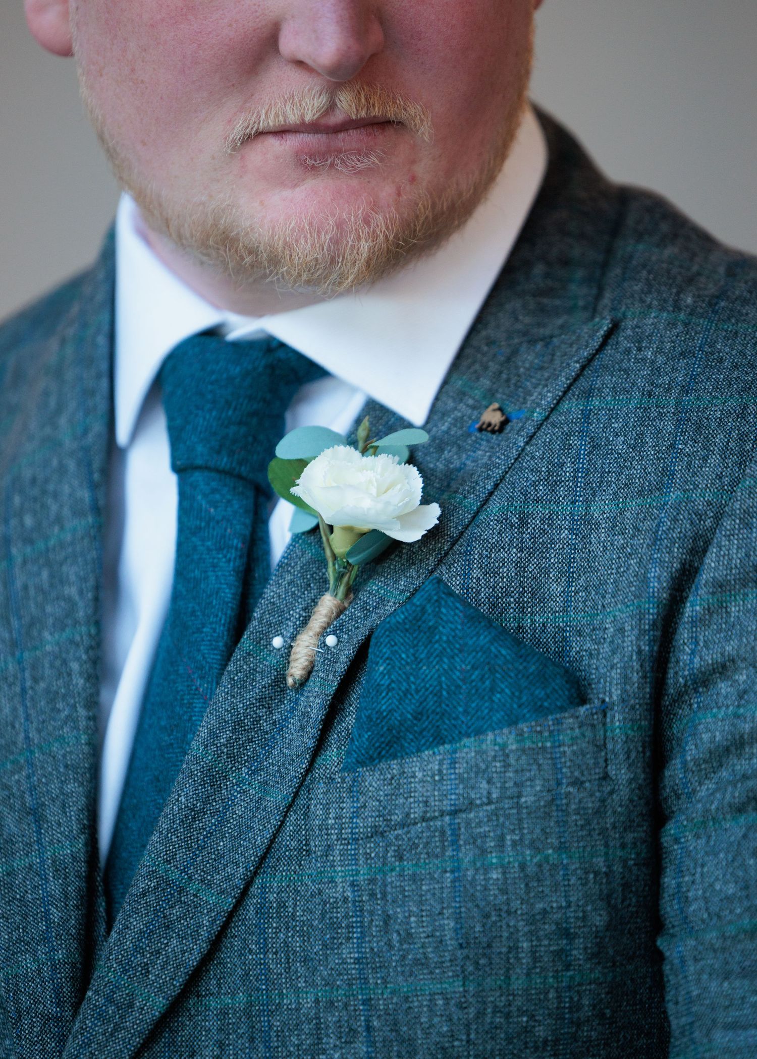 A series of close-up shots showing a white boutonniere on a grey tweed suit jacket.