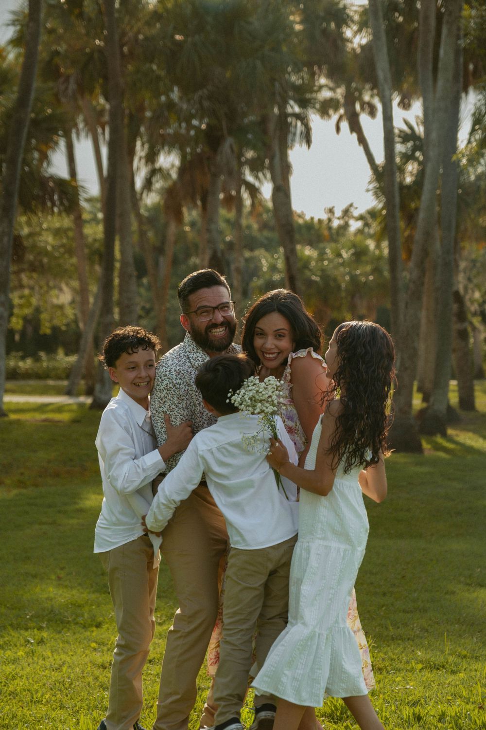 Joyful family portrait in a sun-drenched park with Spanish moss draped trees.