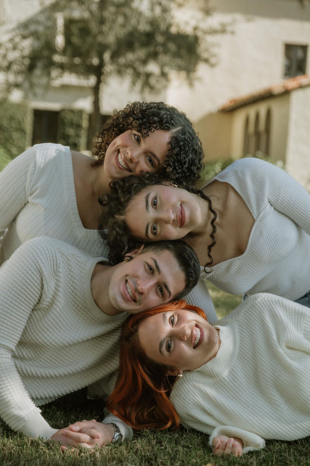 Two people in white sweaters sharing intimate moment while lying down outdoors.