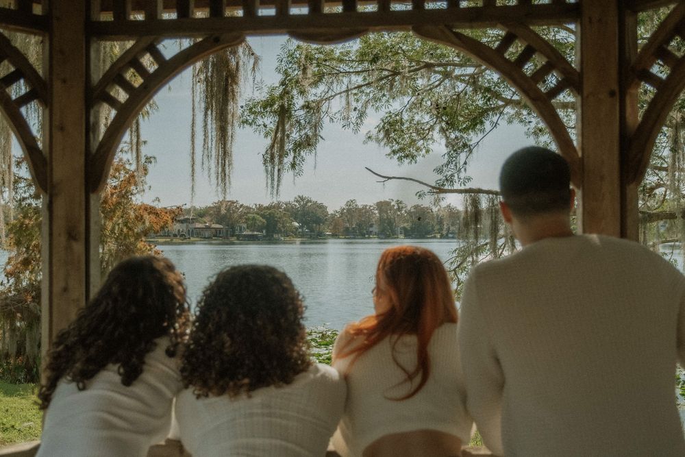 family sitting together on a gazebo overlooking a lake.