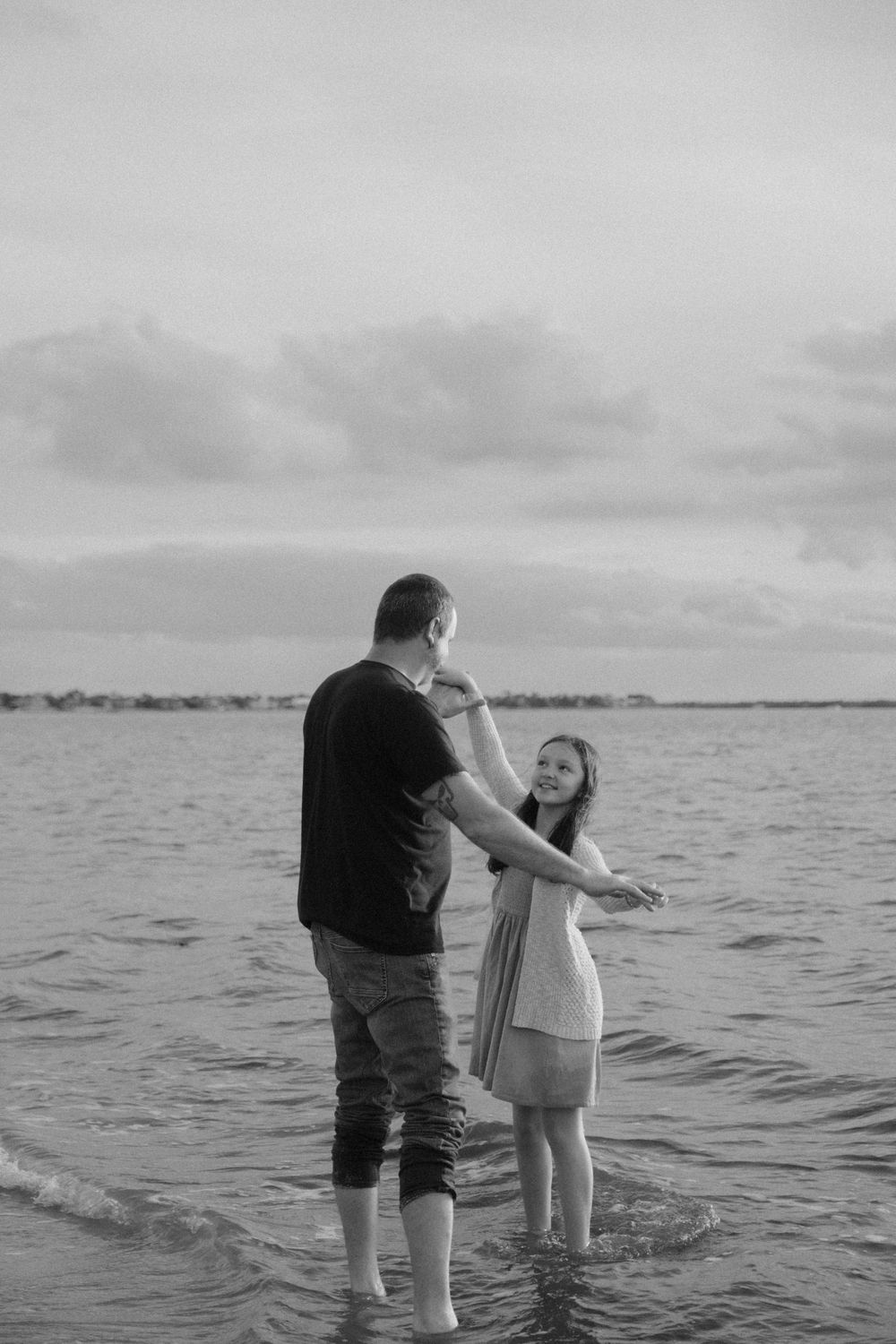Black and white photo of people playing in shallow water at the beach.