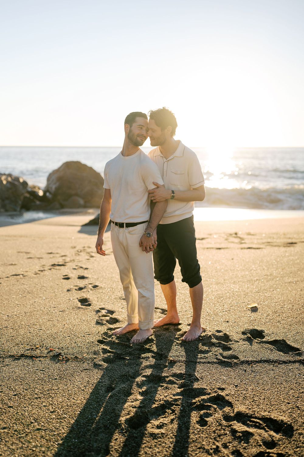 A romantic beach scene at sunset with footprints in the sand and ocean waves in the background.