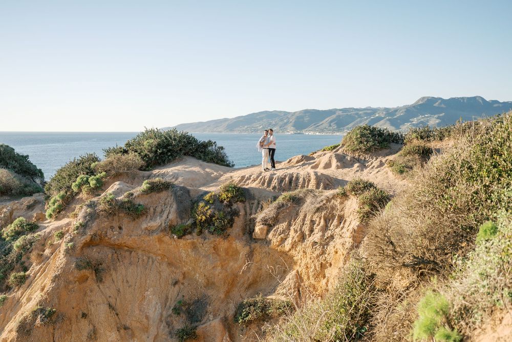 Scenic coastal cliffs and bluffs overlooking the Pacific Ocean with hikers enjoying panoramic views on a clear day.