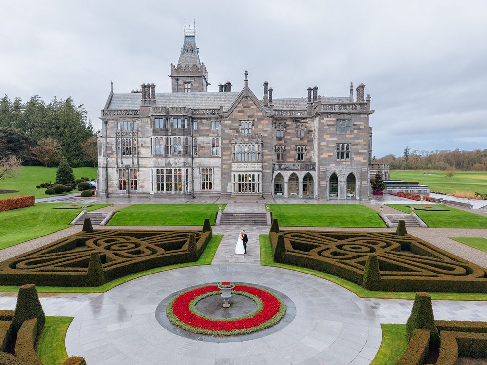Aerial views of a historic mansion with ornate gardens featuring geometric patterns and a circular fountain centerpiece.