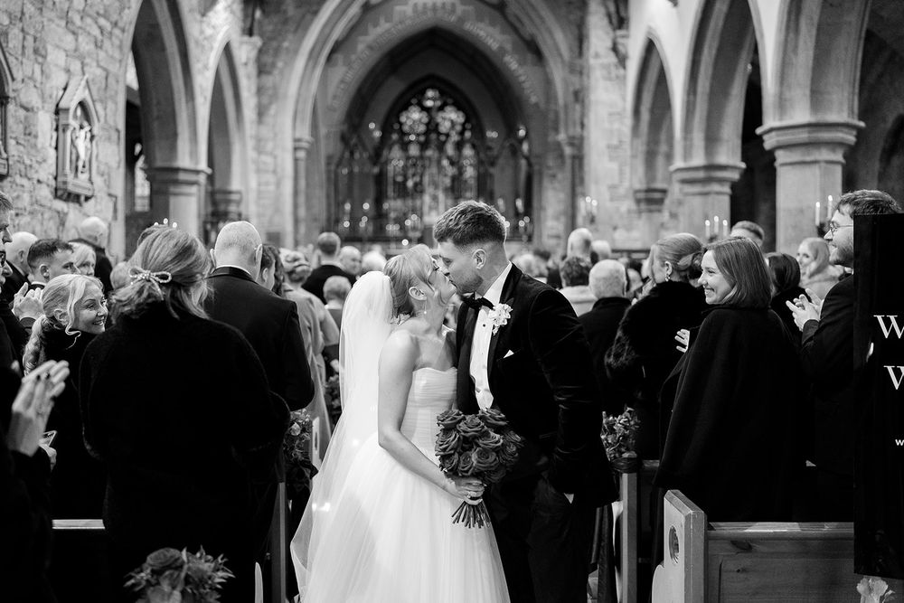 A wedding ceremony takes place inside a grand cathedral with ornate stone architecture and stained glass windows.