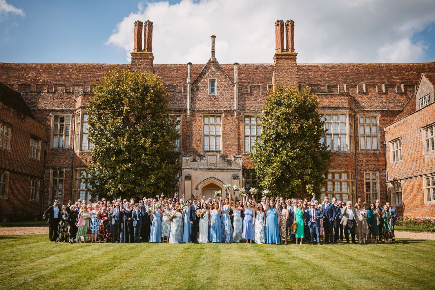 Panoramic view of a Mapledurham, historic brick mansion with large group gathered on the lawn for a wedding celebration.