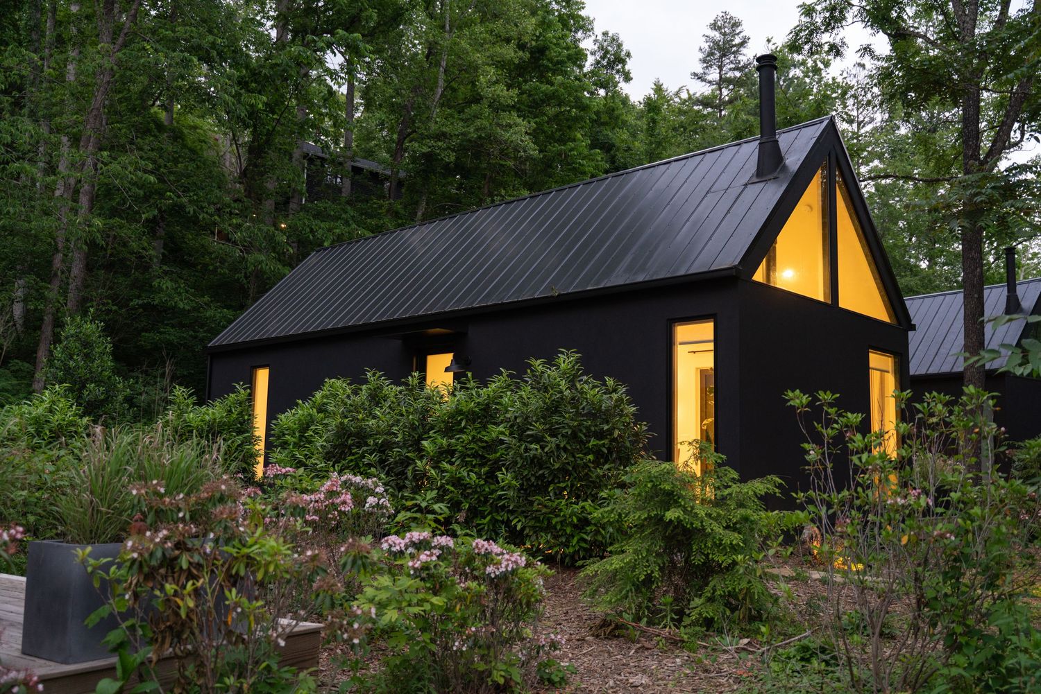 One of the cabins at Firelight at Shope Creek lit up at dusk with spring flowers blooming in the foreground