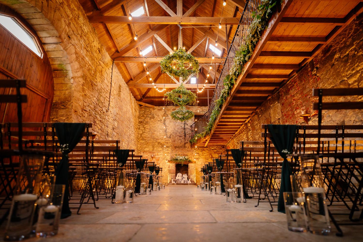 Rustic barn wedding venue interior with exposed wooden beams and rows of chairs set for ceremony.