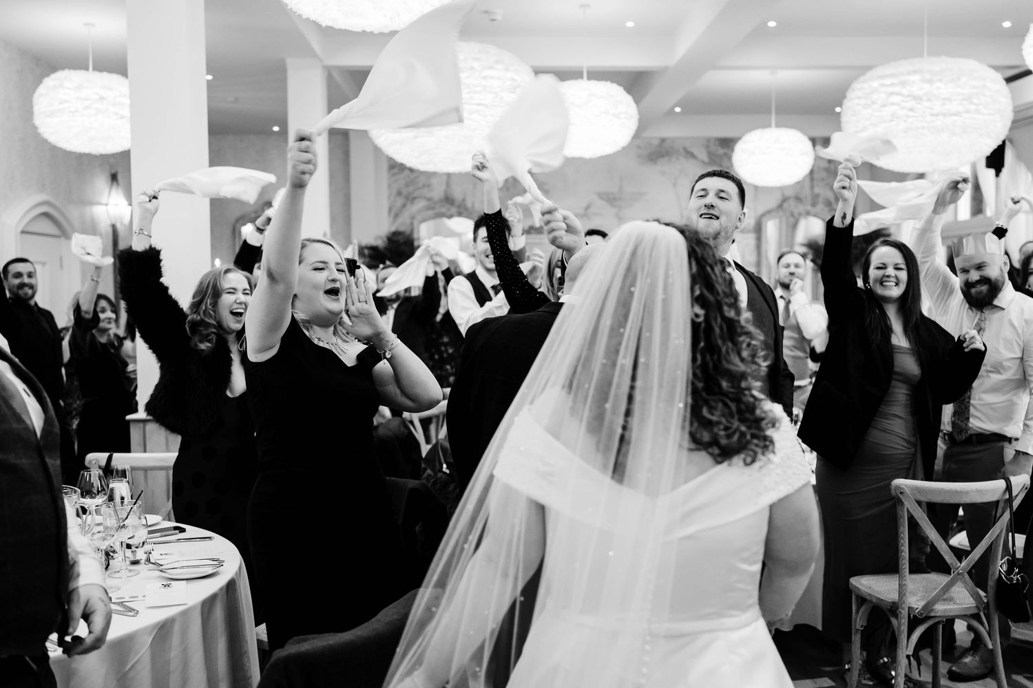 A wedding reception celebration with guests dancing and cheering to the entrance of the bride at Wennington Hall Christmas Wedding