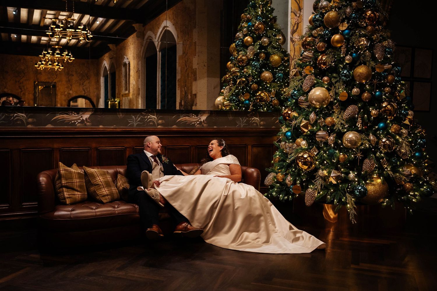 Wennington Hall Christmas wedding captured by Lynette Matthews Photography - Bride & Groom relaxing on the sofa next to Christmas tree