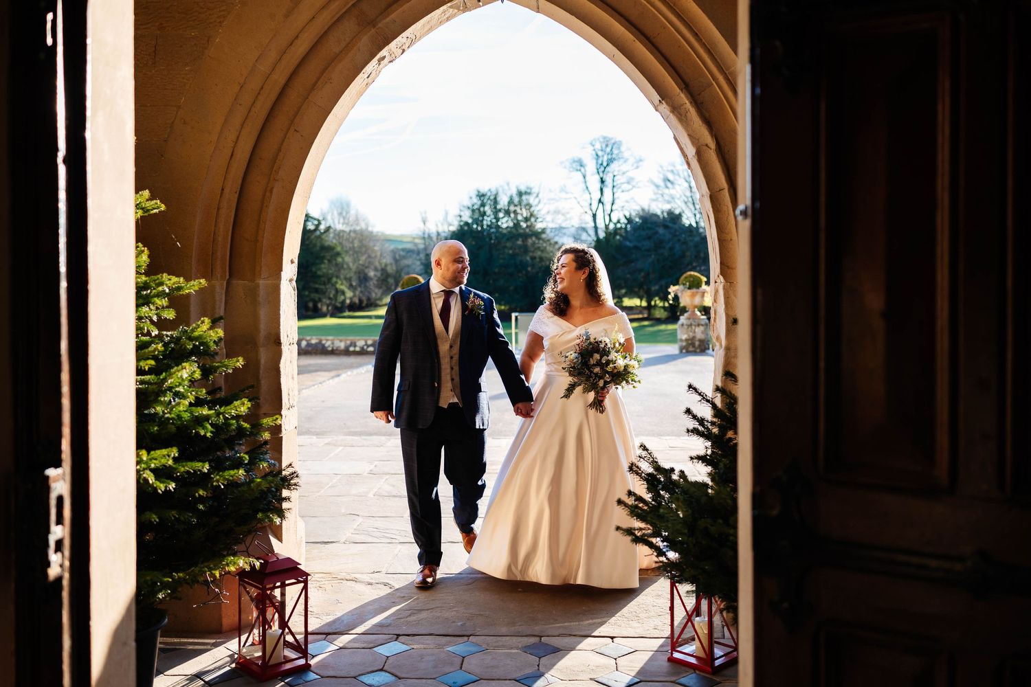 bride and groom walk through door way at Wennington Hall during their Christmas Wedding captured by Lynette Matthew Photography