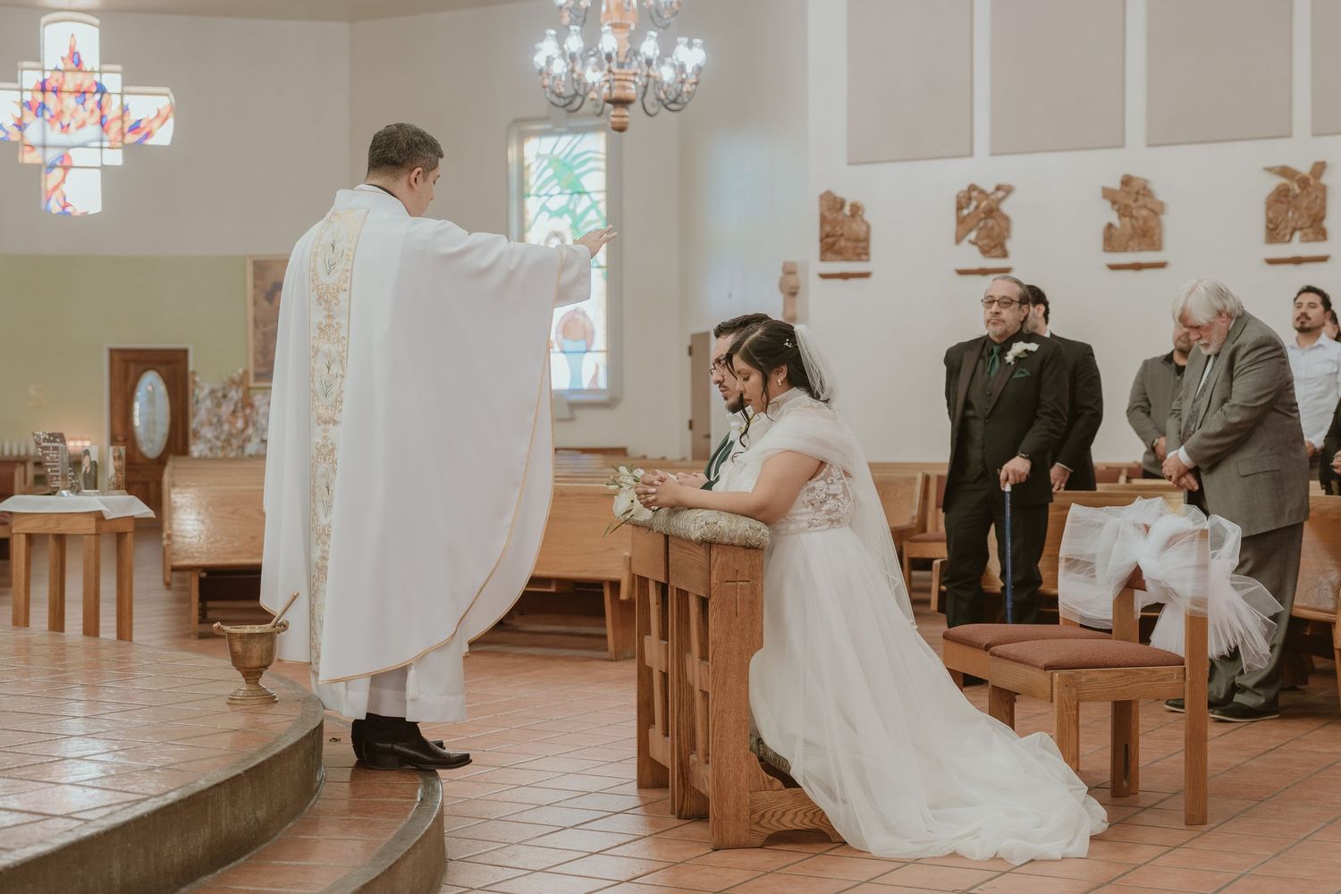 A man and woman recieve blessing from a priest in a church wedding ceremony
