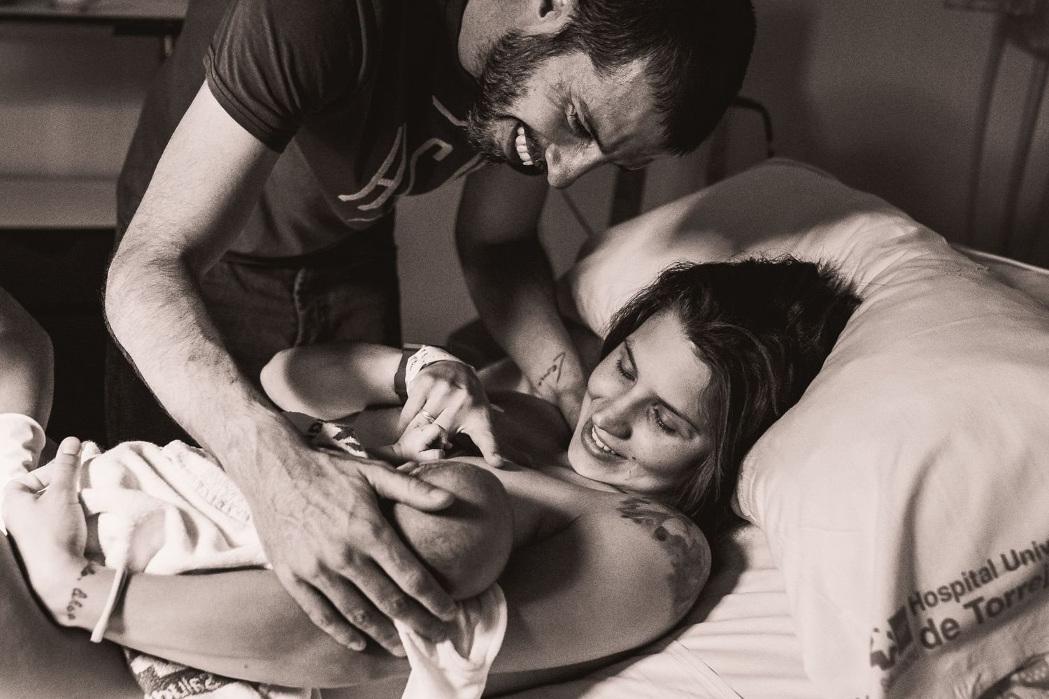 Intimate hospital birth photography capturing raw emotions in black and white.