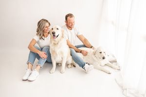 A white dog poses with people in casual outfits against a white backdrop in a series of studio photos.