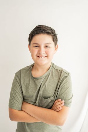 A person in a gray t-shirt poses with crossed arms against a white background in a series of similar shots.