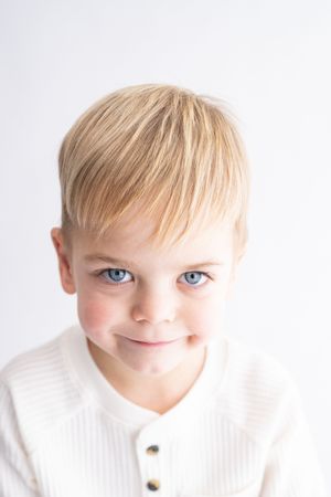 Three close-up photos of a young child with blonde hair and blue eyes wearing a white shirt.