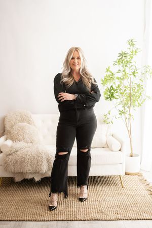Woman in black outfit poses in four different positions on a neutral beige rug with white furniture and plants.