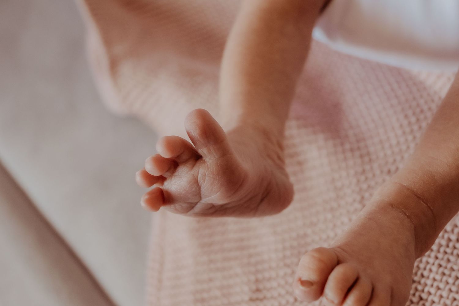 Close-up shot of small baby's feet on pink textured fabric at a central coast newborn photoshoot.